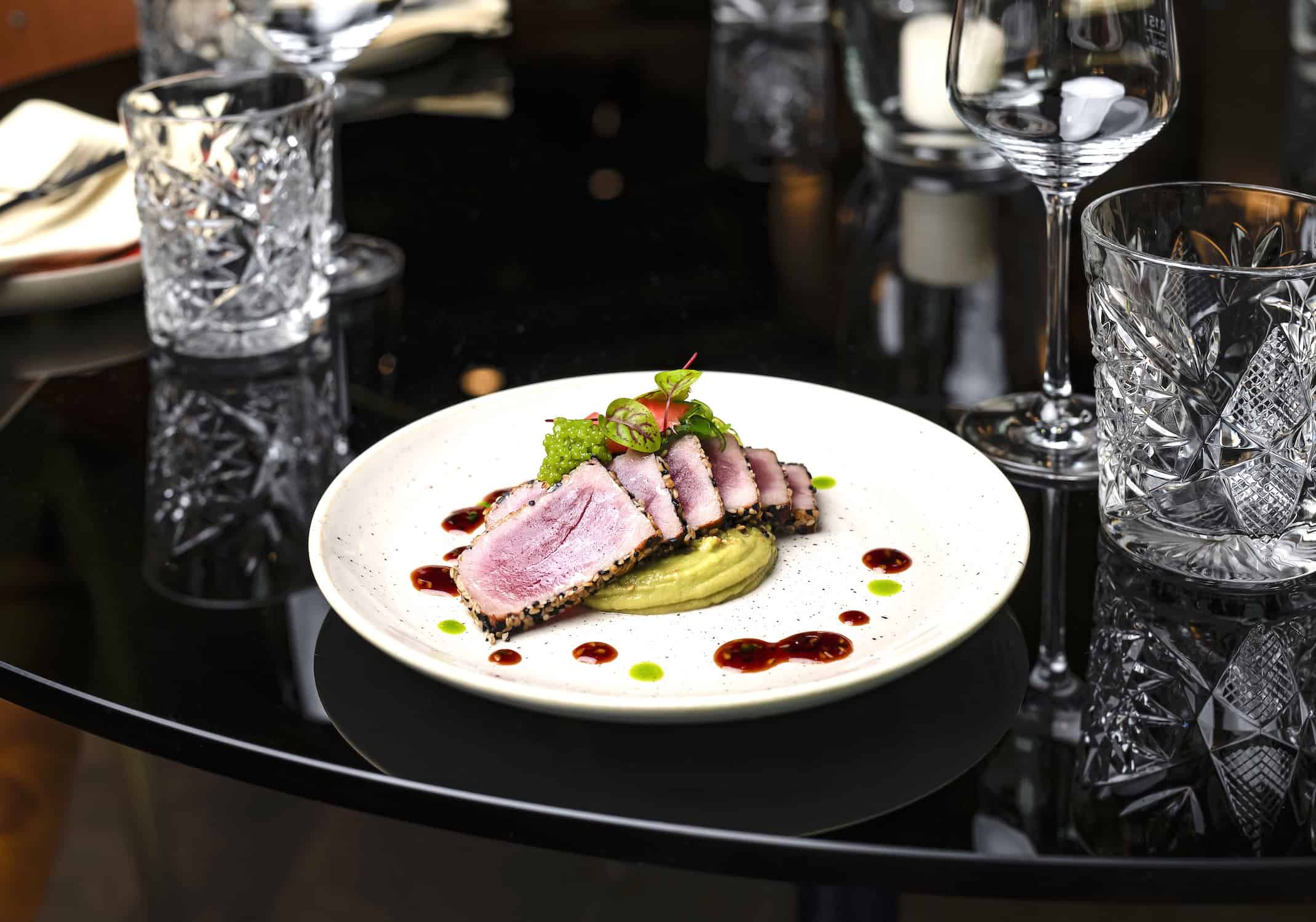 Saftiges Sushi mit Sesamkruste auf einem schwarzen Tisch, stilvoll gedeckte Bar in Frankfurt.